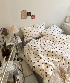 a bed with white sheets and red hearts on it next to a window in a bedroom