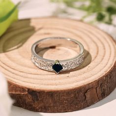 a close up of a ring on a piece of wood with leaves in the background