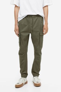 Joggers in woven cotton fabric. Waistband with drawstring and covered elastic. Diagonal side pockets  back pockets with flap and concealed snap fasteners  and leg pockets with flap and concealed snap fasteners. Tapered legs with seams and darts at knees and covered elastic at hems. Tapered Leg Cotton Cargo Jeans, Cotton Cargo Pants With Multiple Pockets And Tapered Leg, Cotton Tapered Leg Cargo Pants With Multiple Pockets, Cotton Cargo Pants With Tapered Leg And Cargo Pockets, Casual Cotton Cargo Pants With Hip Pockets, Cotton Cargo Pants With Tapered Leg And Side Pockets, Casual Cotton Cargo Pants With Pockets, Military Cotton Bottoms With Cargo Pockets, Casual Tapered Leg Cotton Cargo Jeans