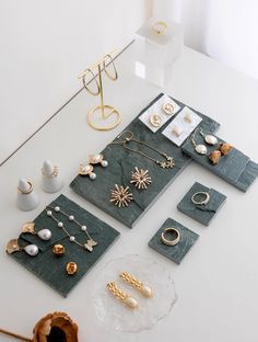 a table topped with lots of jewelry on top of a white counter next to a vase