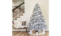 a white christmas tree in the corner of a room with stairs and banisters