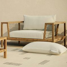 a wooden couch with pillows on top of it next to a chair and side table