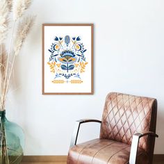 a brown leather chair sitting in front of a white wall next to a green vase