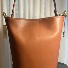 Coach Glovetanned Leather Dakota Bucket Bag Medium Sized Bag; 13-1/2"W X 11-1/2"H X 6"D (Width Is Measured Across The Bottom Of Handbag); 2.0 Lbs. Approx. Weight Silhouette Is Based Off 5'9" Model 10-3/4"L Removable Handle; 21-1/2"L Removable Crossbody Strap Snap Closure Brass-Tone Hardware Interior Zip Pocket Leather Spot Clean Imported Coach Leather Bucket Bag For Daily Use, Coach Bucket Bag With Gold-tone Hardware For Everyday Use, Cognac Bucket Bag With Gold-tone Hardware For Daily Use, Coach Bucket Bag Tote With Gold-tone Hardware, Versatile Brown Bucket Bag With Gold-tone Hardware, Medium Sized Bags, 6 D, Medium Bags, Crossbody Strap