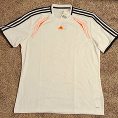 White Adidas Climalite Jersey With Neon Orange Details And Logo Stitching As Well As Black Stripes On The Shoulders And Cuffs. Breathable And Lightweight For The Most Active Sportsman! White Adidas Workout T-shirt, White Breathable Athleisure T-shirt, White Breathable T-shirt For Athleisure, White Adidas Logo T-shirt For Workout, Adidas Logo White T-shirt For Workout, White Adidas Logo Sportswear Tops, White Adidas Sporty T-shirt, Adidas White Sporty T-shirt, White Adidas Logo Crew Neck Activewear