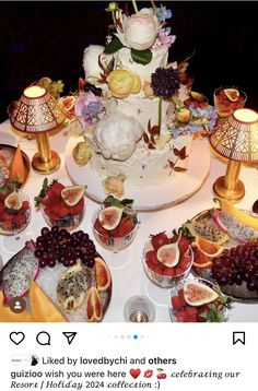 a wedding cake surrounded by fruit and flowers on a table with other desserts around it