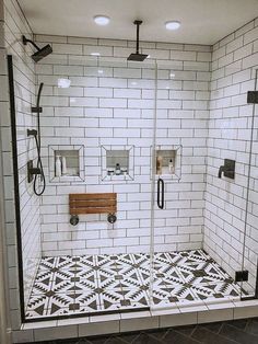 a white tiled bathroom with black and white tiles on the floor, shower head, and toilet