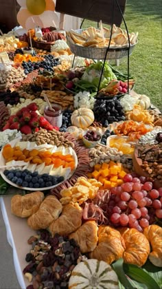 an assortment of fruits and pastries on a buffet table with balloons in the background