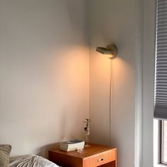 a bed room with a neatly made bed and a lamp on the wall next to it