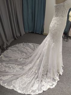 a white wedding dress on display in front of curtains