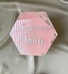 a pink happy birthday name sign sitting on top of a bed