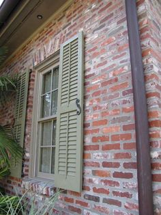 a brick building with green shutters and a window