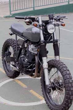 a motorcycle parked in a parking lot next to a fence