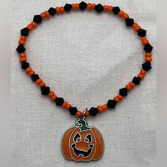 a beaded necklace with an orange and black pumpkin charm on it's clasp