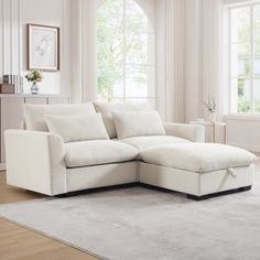 a living room with a large white sectional couch in the middle of it and a rug on the floor