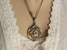 "A brushed bronze round locket is adorned with a garland of tiny roses and flourishes of leaves around it's perimeter. A six petal flower is placed in the center of the front. A ribbed bail holds the locket on a 20\" bronze cable link chain closed with a lobster clasp. The chain in enhanced with a small scrolling connector near the bail. The reverse side of the locket is plain brushed finish with a soft glow. If you prefer a different length chain, please let me know. This 32mm (1 1/4\") round l Bronze Locket Jewelry For Wedding, Wedding Locket Necklace In Metal, Wedding Metal Locket Necklace, Bronze Round Pendant Necklace For Wedding, Bronze Vintage Charm Jewelry For Wedding, Elegant Bronze Locket Necklace For Wedding, Antique Finish Round Pendant Necklace For Weddings, Bronze Locket Necklace With Vintage Charm For Wedding, Bronze Antique Finish Jewelry For Wedding