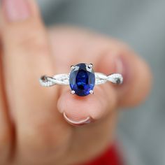 a woman's hand holding a ring with a blue stone