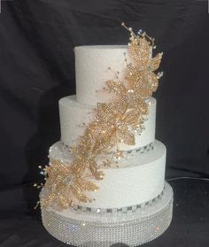 a three tiered wedding cake with gold leaves on top