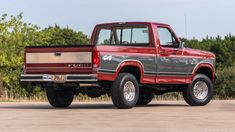 a red pick up truck parked in front of some trees