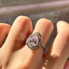 a woman's hand with a pink diamond ring on it