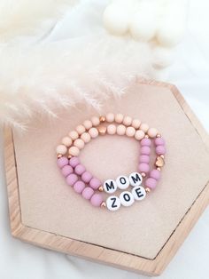 two beaded bracelets with the word mom zone spelled in white and pink beads