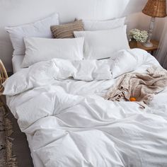 an unmade bed with white sheets and pillows