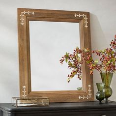 a mirror sitting on top of a dresser next to a vase with flowers in it