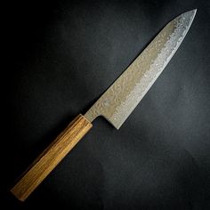 a large knife with a wooden handle on a black surface