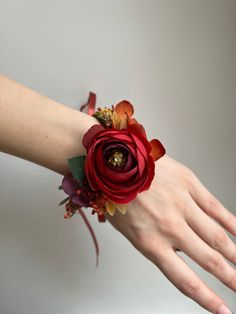 a woman's hand wearing a red wrist corsage