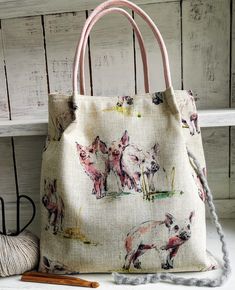 a small bag with pigs on it next to yarn and knitting crochet hooks