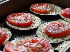 some tomatoes and other vegetables are in a pan with seasoning on them, ready to be cooked