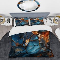 a bed with blue and gold marble pattern on the comforter, along with two pillows