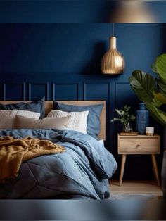 a bed with blue sheets and pillows in a bedroom next to a potted plant