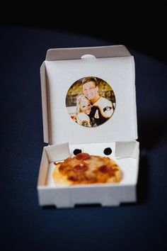 an open pizza box with a slice of pizza in it and a photo on the lid