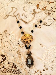 0My inspiration for this necklace was a single gold filled black and white onyx cameo genuine gold filled Victorian earring and a Victorian  gold and black enamel neck pin. i hung them from antique jet beads and the chain is a a vintage chain and clasp. is a very delicate look. part of my tiny treasures collection  The necklace is 18" long and the cameo piece is 1" Elegant Luxury Cameo Necklace, Antique Oval Jewelry With Black Enamel, Antique Oval Black Enamel Jewelry, Elegant Black Jewelry With Antique Finish, Antique Oval Onyx Jewelry, Victorian Jewelry With Antique Finish, Cameo Medallion For Jewelry Making, Victorian Oval Jewelry For Vintage Events, Victorian Black Pendant Jewelry