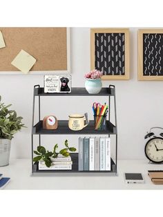 a book shelf with books and other items on it next to a clock, potted plant and two framed pictures