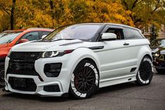 a range rover parked in a parking lot next to other cars with trees in the background