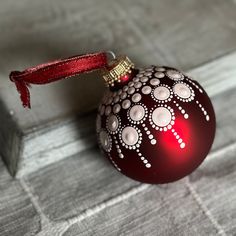 a red ornament sitting on top of a gray table next to a box