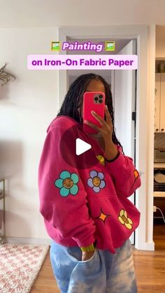 a woman taking a selfie with her cell phone in front of the camera while wearing a pink flowered sweatshirt