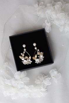 a pair of white flowers and pearls are in a black box