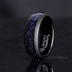 a black ring with blue glitter inlaying the center and words engraved on it