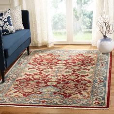 a living room with a blue couch and red rug