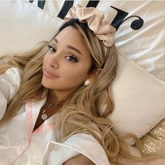 a woman laying on top of a bed wearing a white shirt and pink bow tie