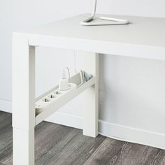 an electronic device is plugged into the side of a white table next to a wall