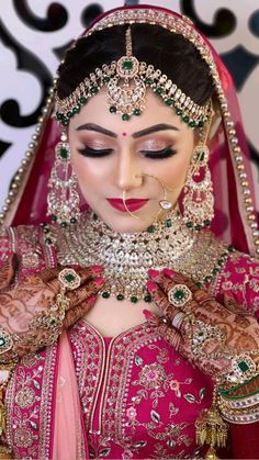 a woman in a pink bridal outfit with jewelry on her head and hands,