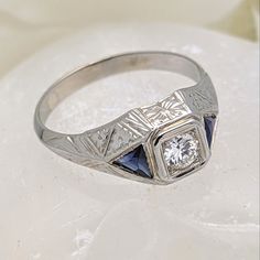 a diamond and blue sapphire ring sitting on top of a white surface