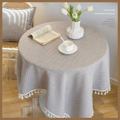 a table with a book, cup and saucer on it next to a chair