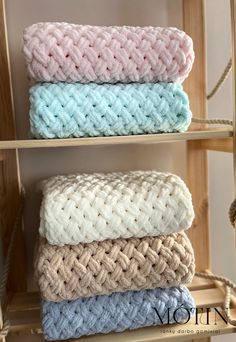 three different colored towels are stacked on top of each other in a rack with rope