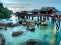 the water is crystal blue and clear with rocks in front of houses on stilts