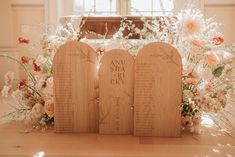 three wooden plaques sitting on top of a table with flowers in front of the doors